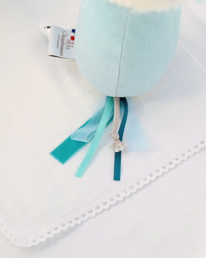 Light blue baby plush toy with ribbons on a white background