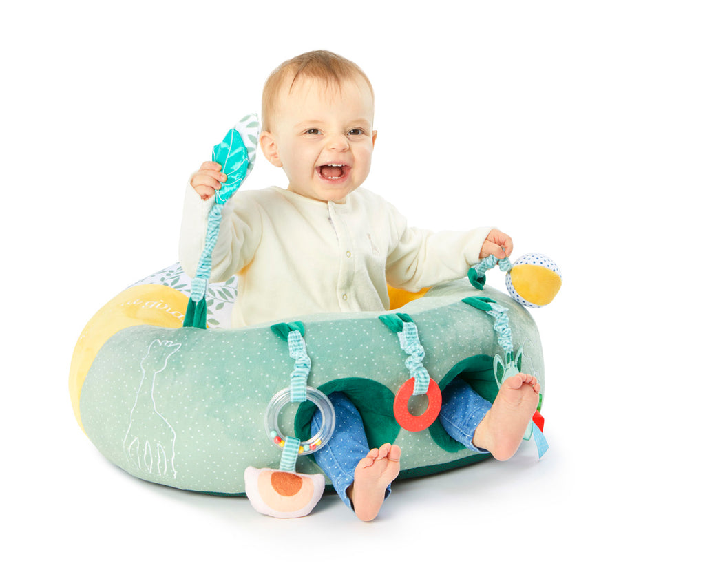 A laughing baby playing with the toys on a Sophie the Giraffe themed baby seat