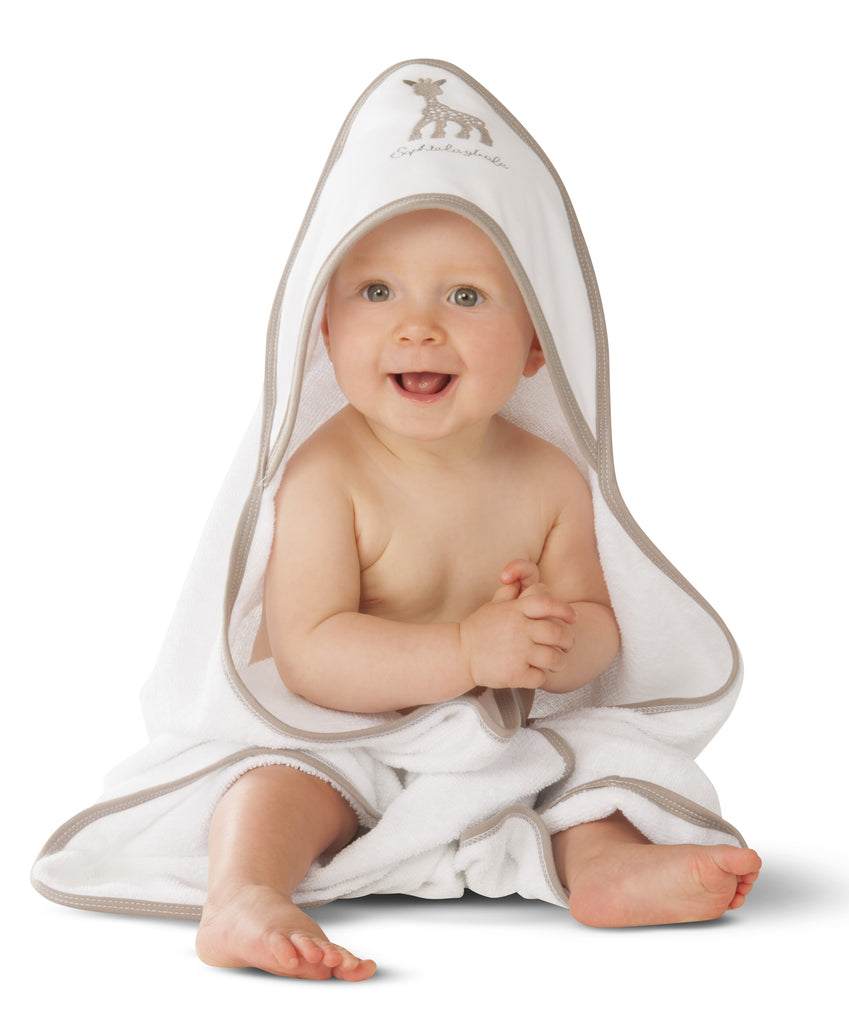 Smiling baby wearing a white hooded bath towel with sophie the giraffe design