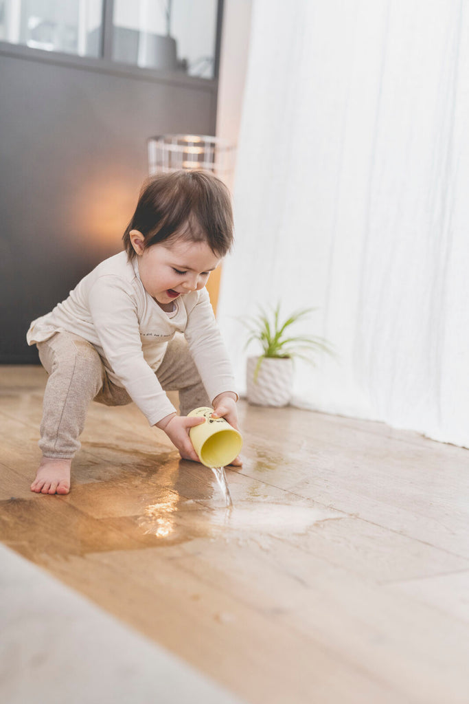 Baby pouring water onto the ground with sophie silicone cup