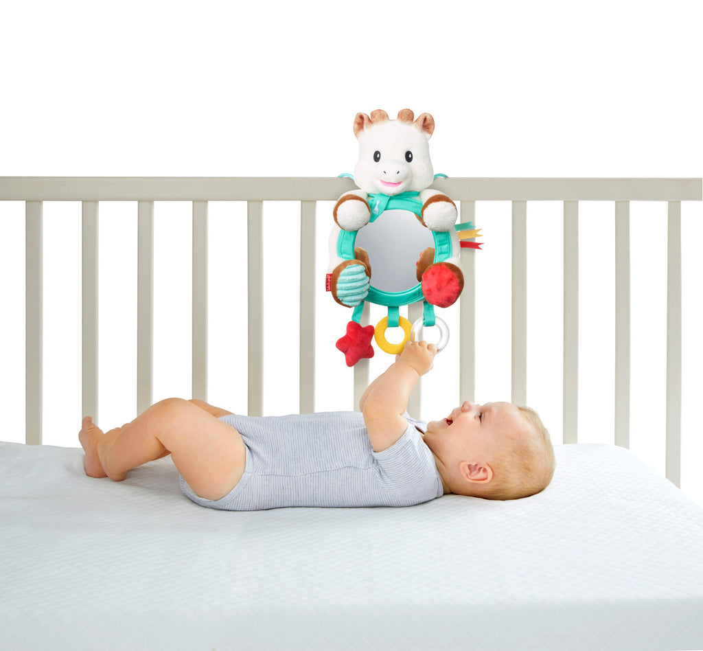 Sophie activities mirror mounted in crib for baby to play with rattle, teether, and textures