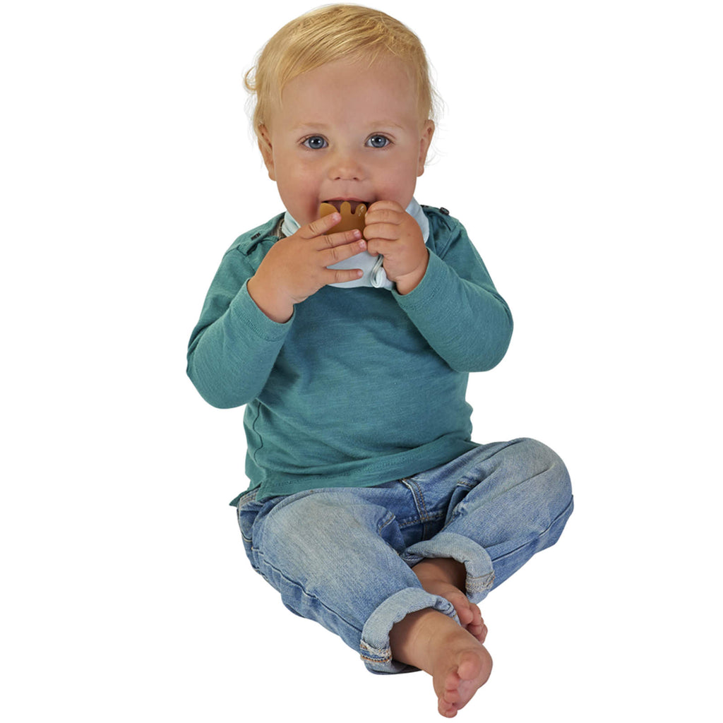 A baby wearing a blue sophie the giraffe bandana and teething on rubber