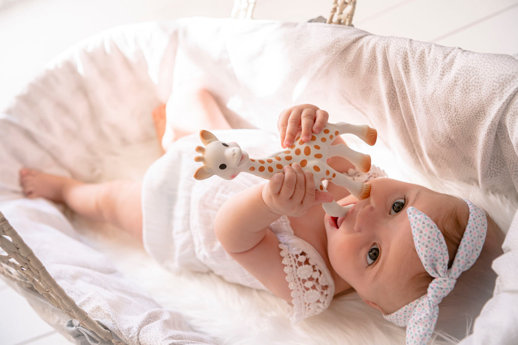 Baby in crib teething on sophie la girafe