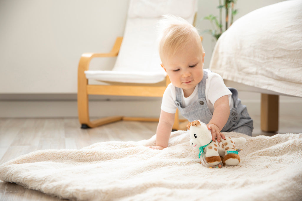 Baby playing with sophie plush with beads