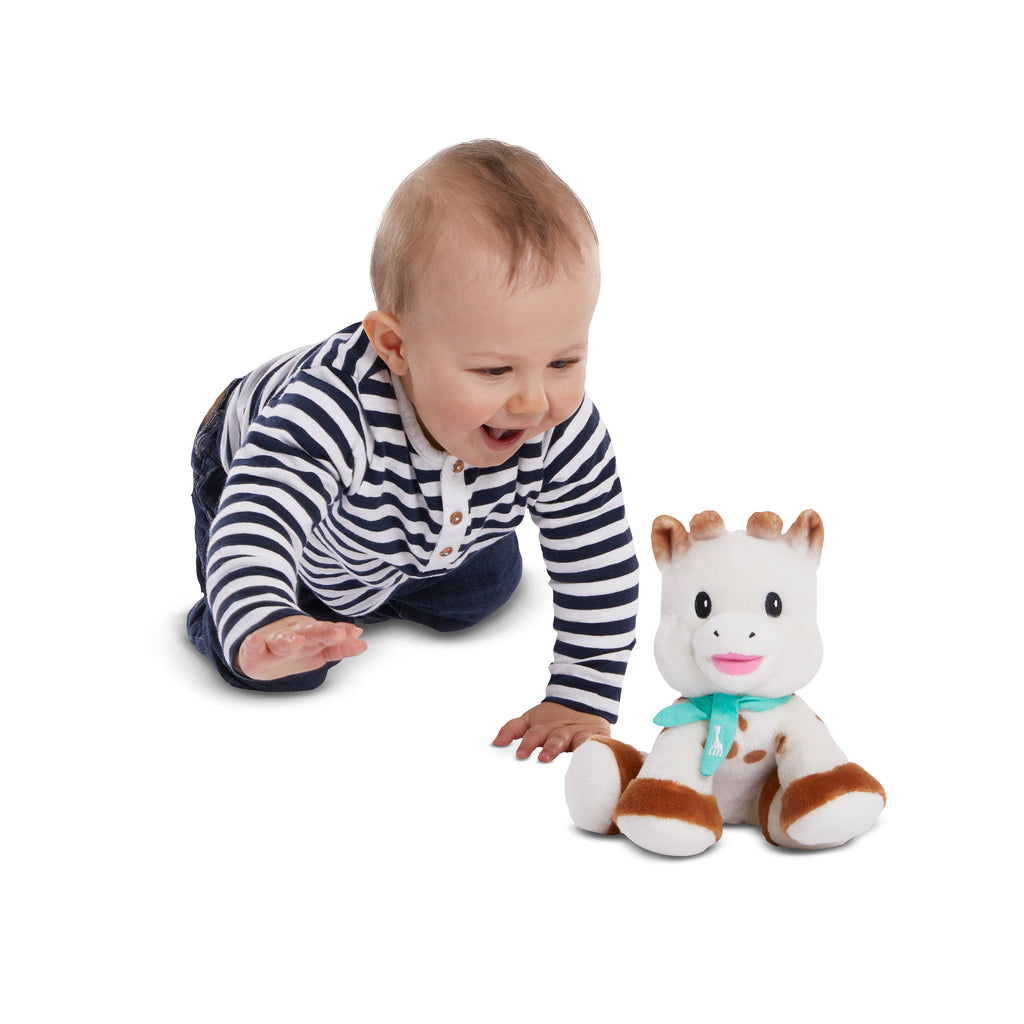 Smiling baby playing with sophie sweetie baby plush