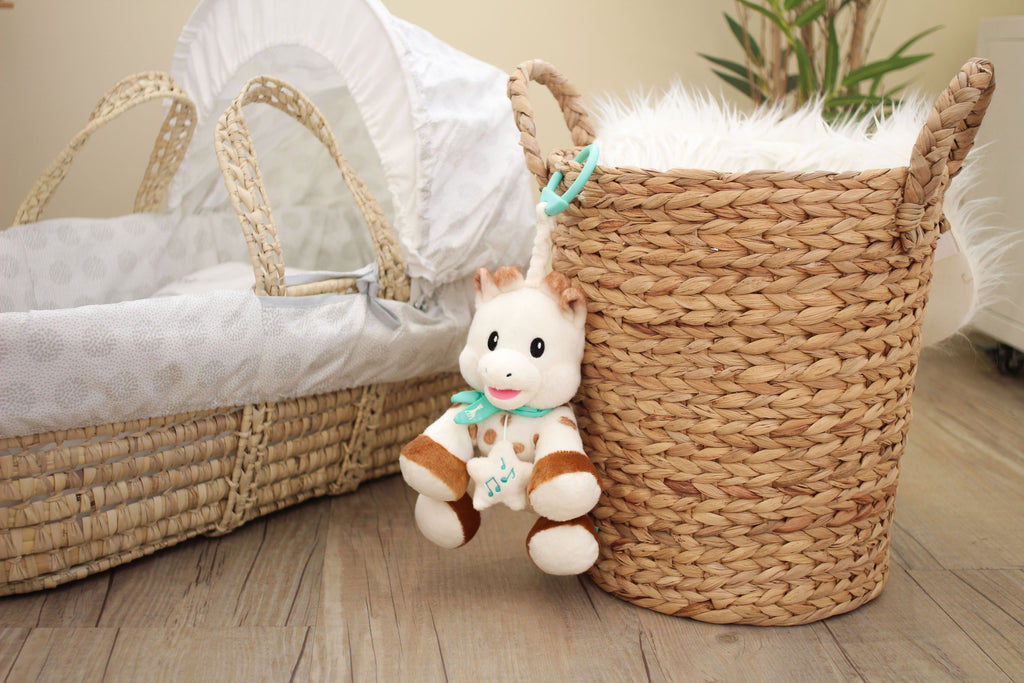 Sophie sweetie musical plush hanging on basket next to baby crib