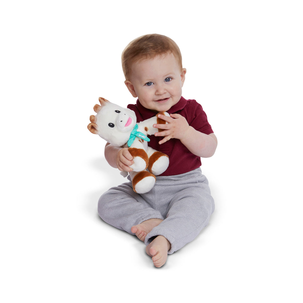 Smiling baby holding sophie sweetie plush