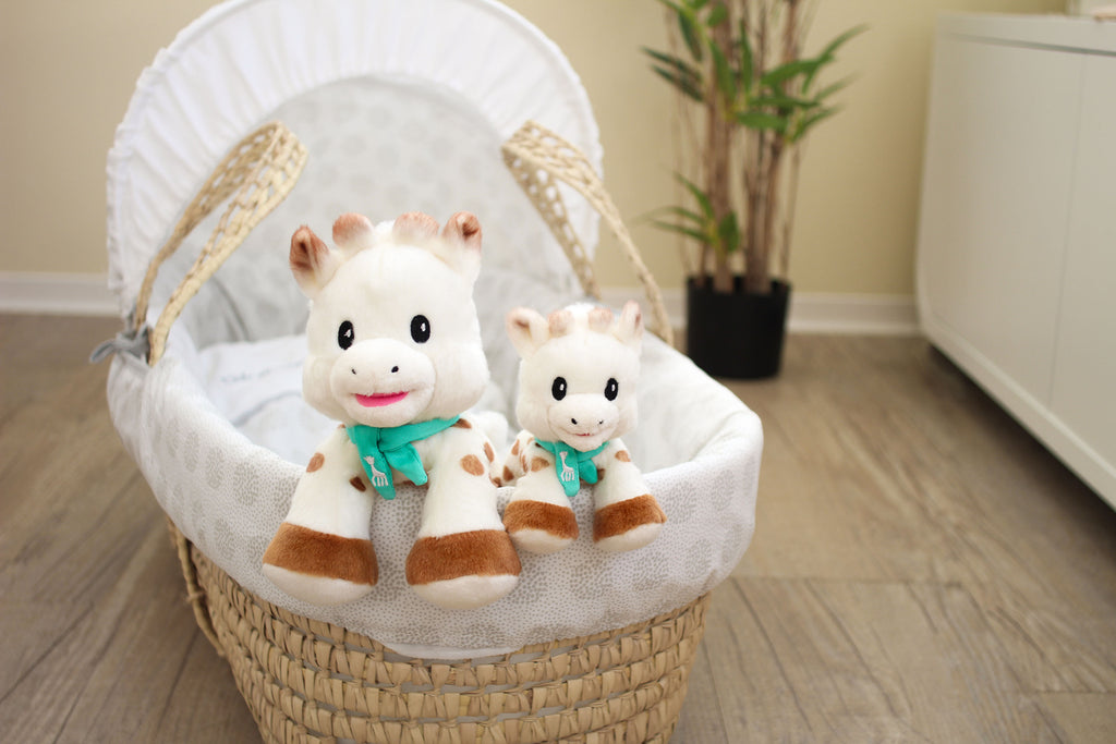 sophie sweetie medium and small plush sitting in a baby crib